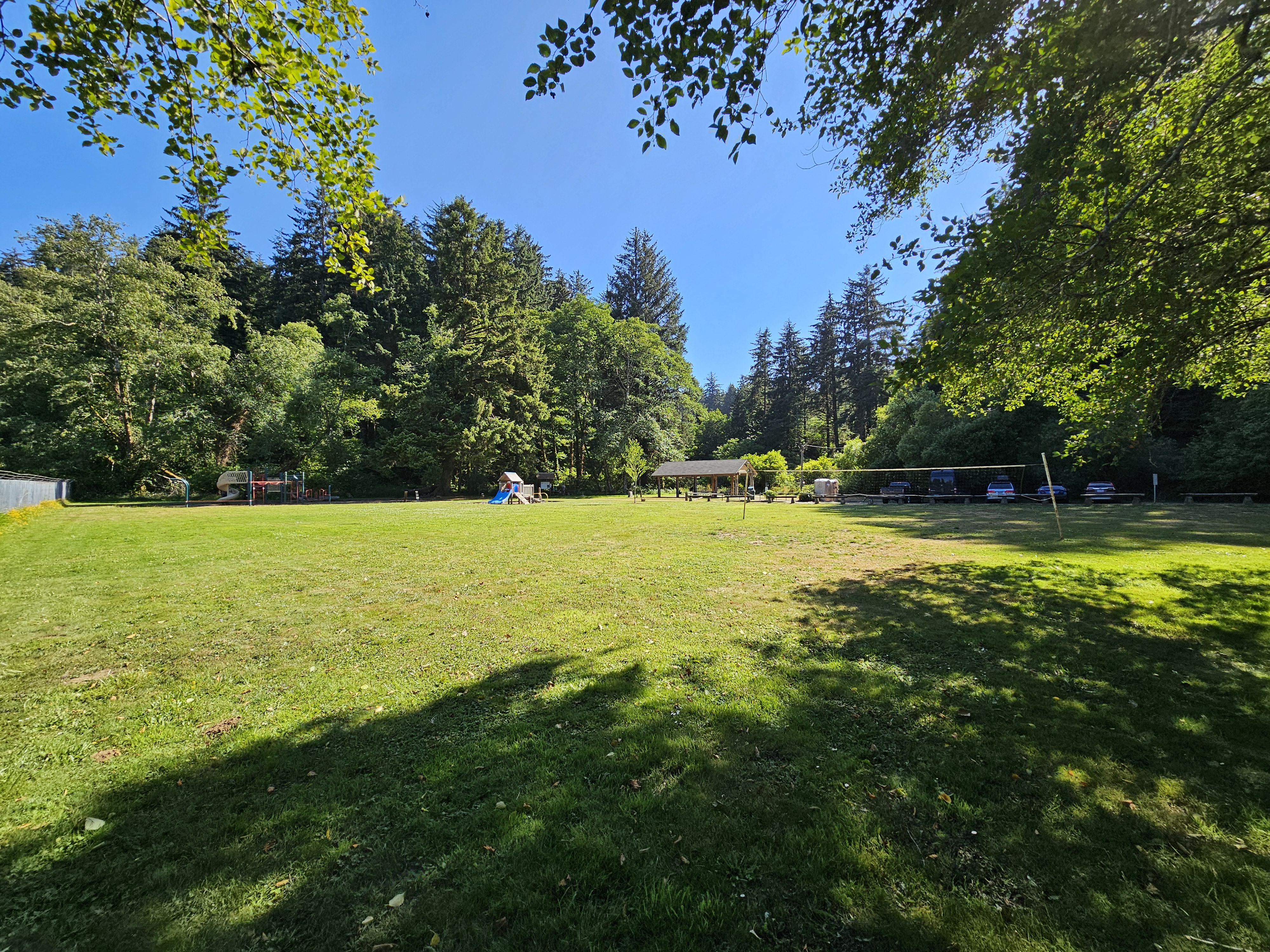 large field showing parking lot, playground, picnic shelter, port-a-potties, and volleyball nets