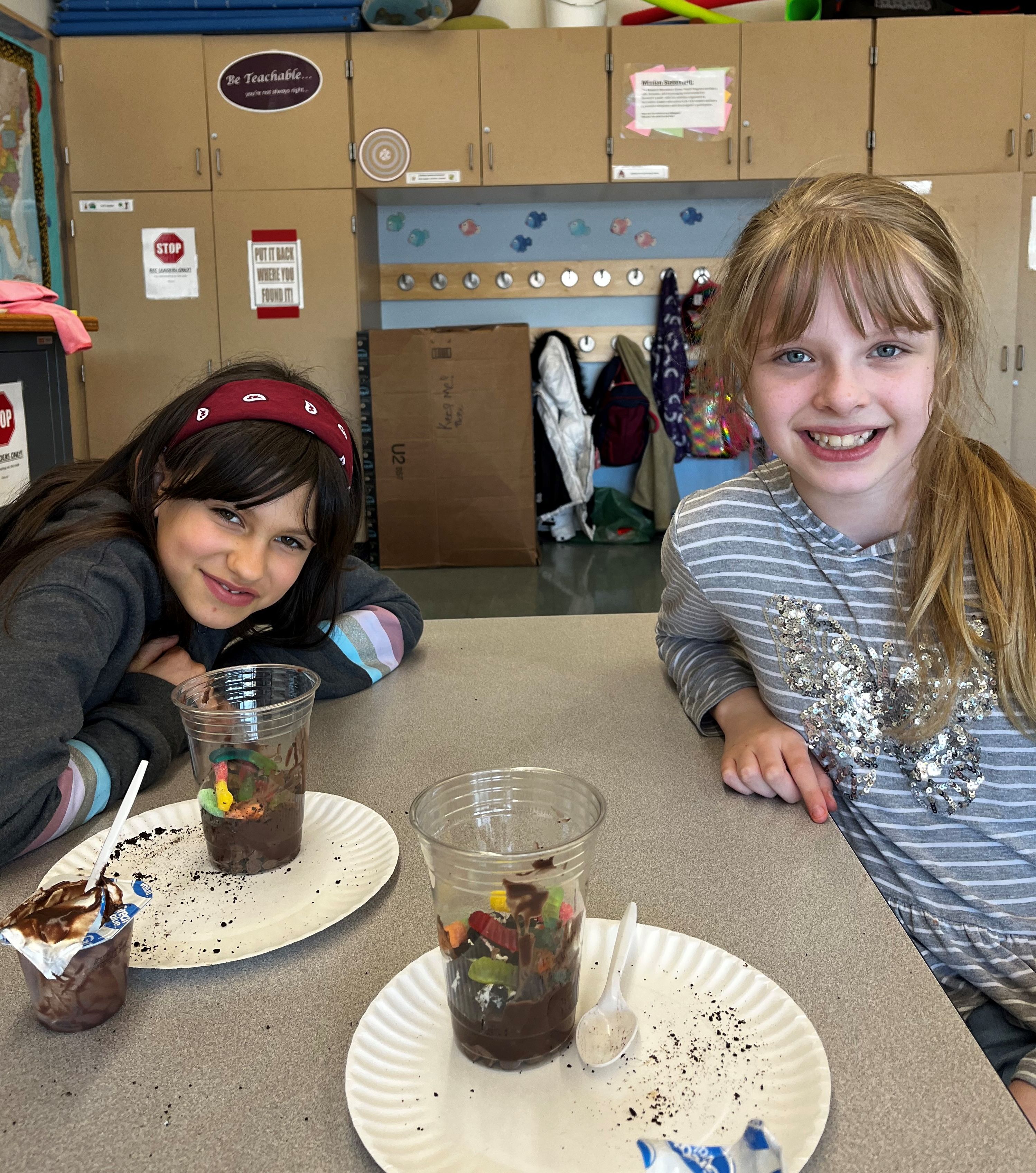 two girls having fun making soil models using pudding and gummy worms