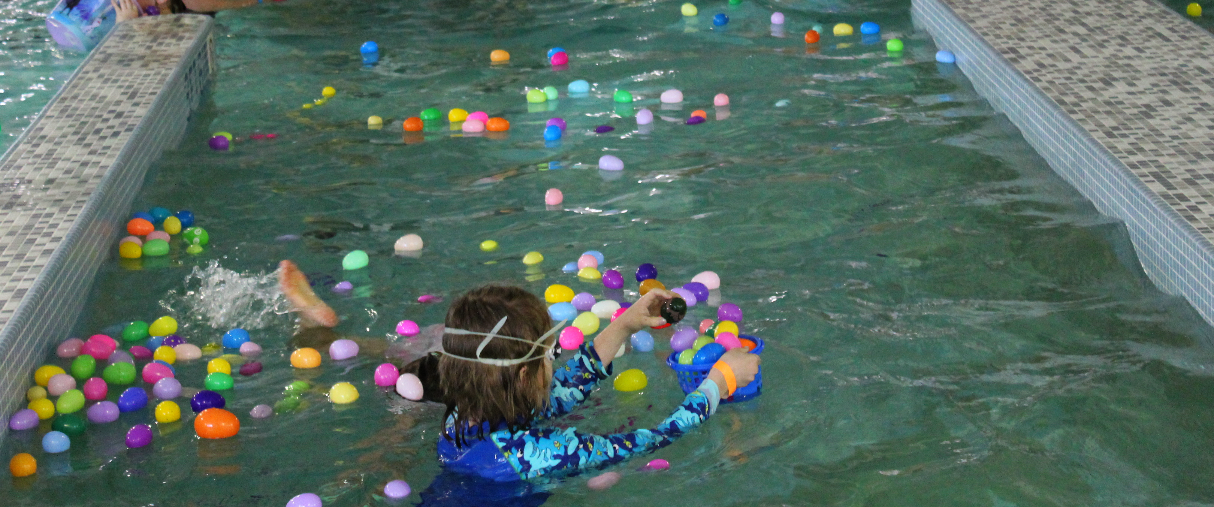 child in pool with floating eggs